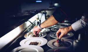 Two adult hands placing food onto plate